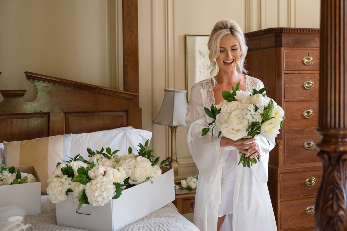 Bride looking delighted at her bridal bouquet of crfeam and white flowers