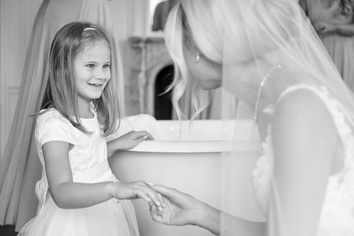 Bride bent down to hold a flower girl's hand
