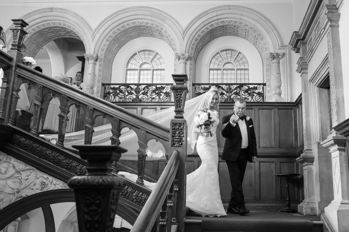 Bride and her dad walking down a grand staircase