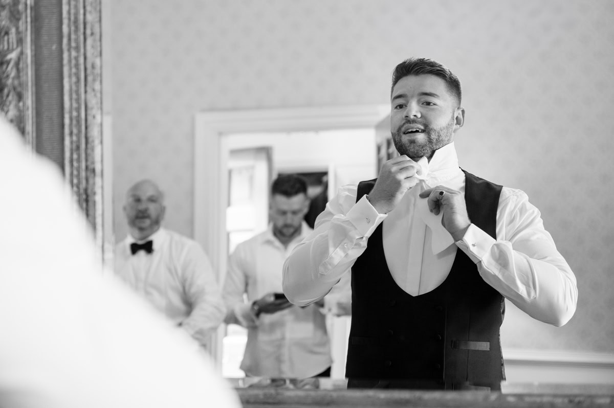 Groom tying a real bow tie in a mirror