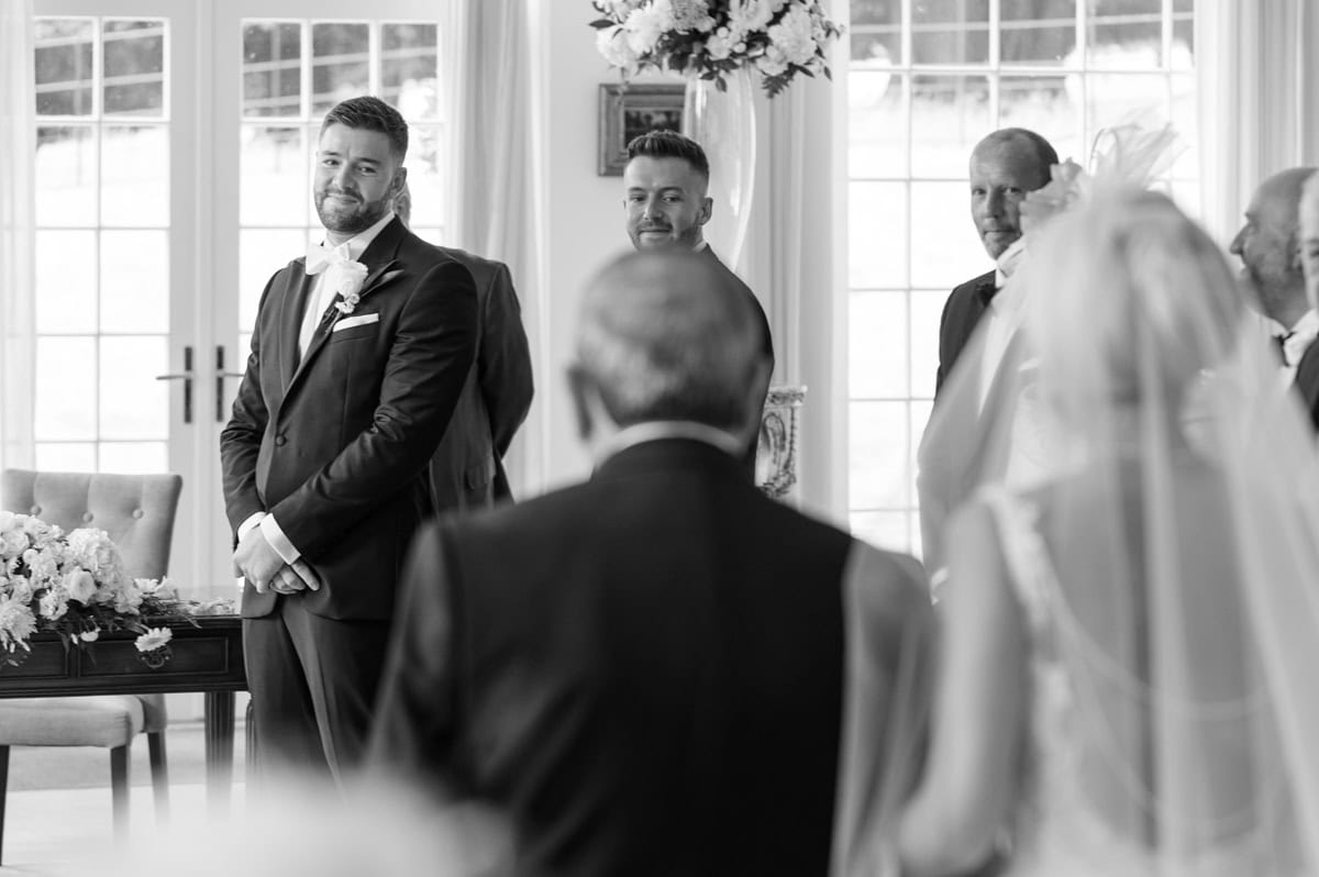 Groom watching the bride walk down the aisle