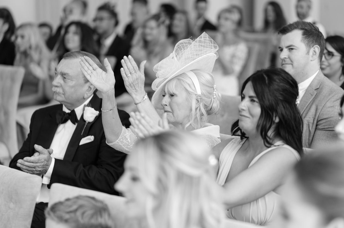 Wedding guests clapping during ceremony in response to someone's reading