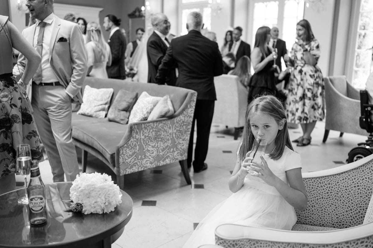 Young flower girl enjoying a drink with a straw in a busy bar lounge area