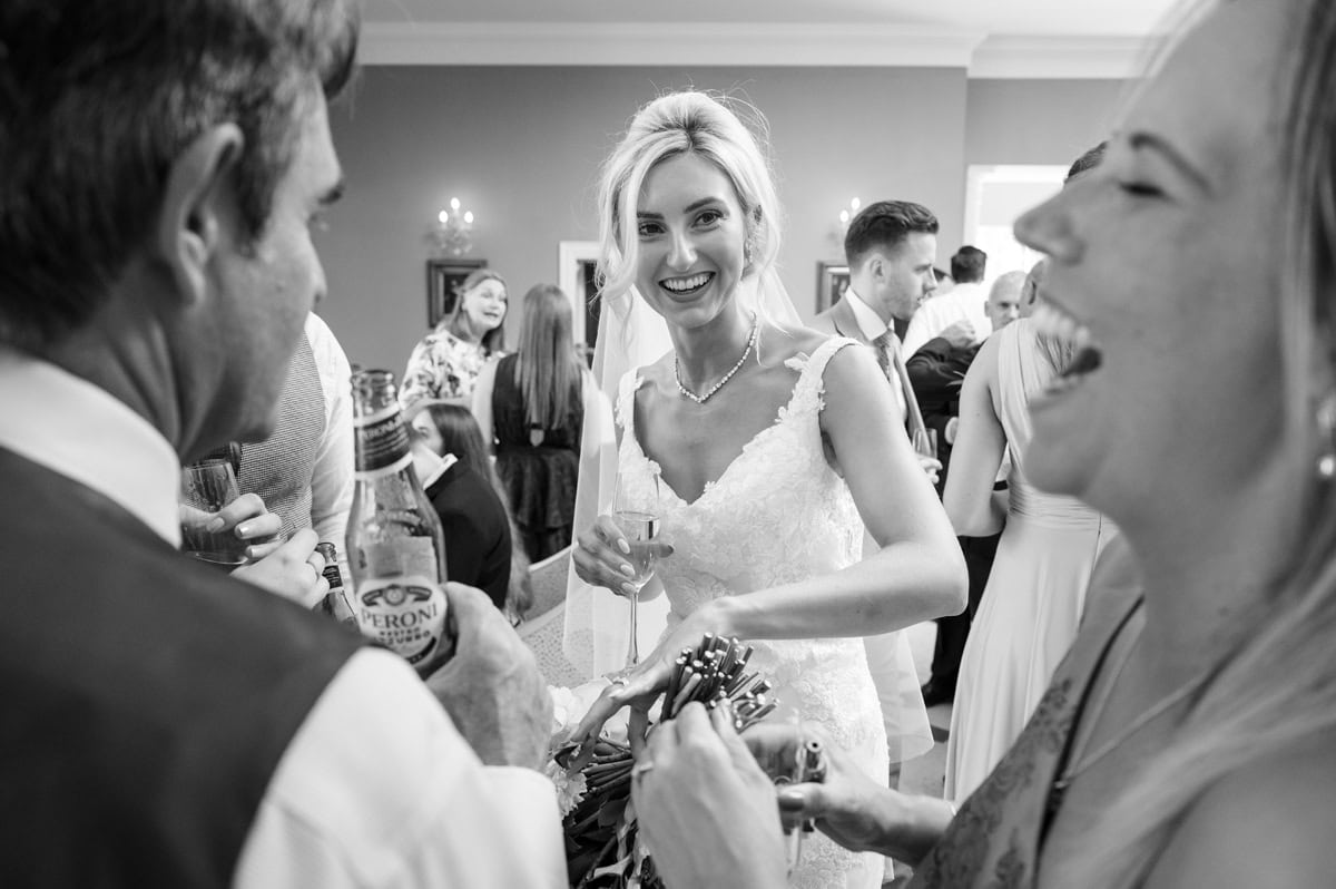 Bride laughing with wedding guests as she shows them her wedding ring