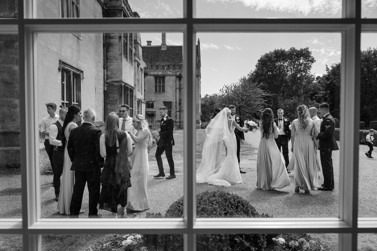 View through a window of a wedding drinks reception in the grounds of a stately country house