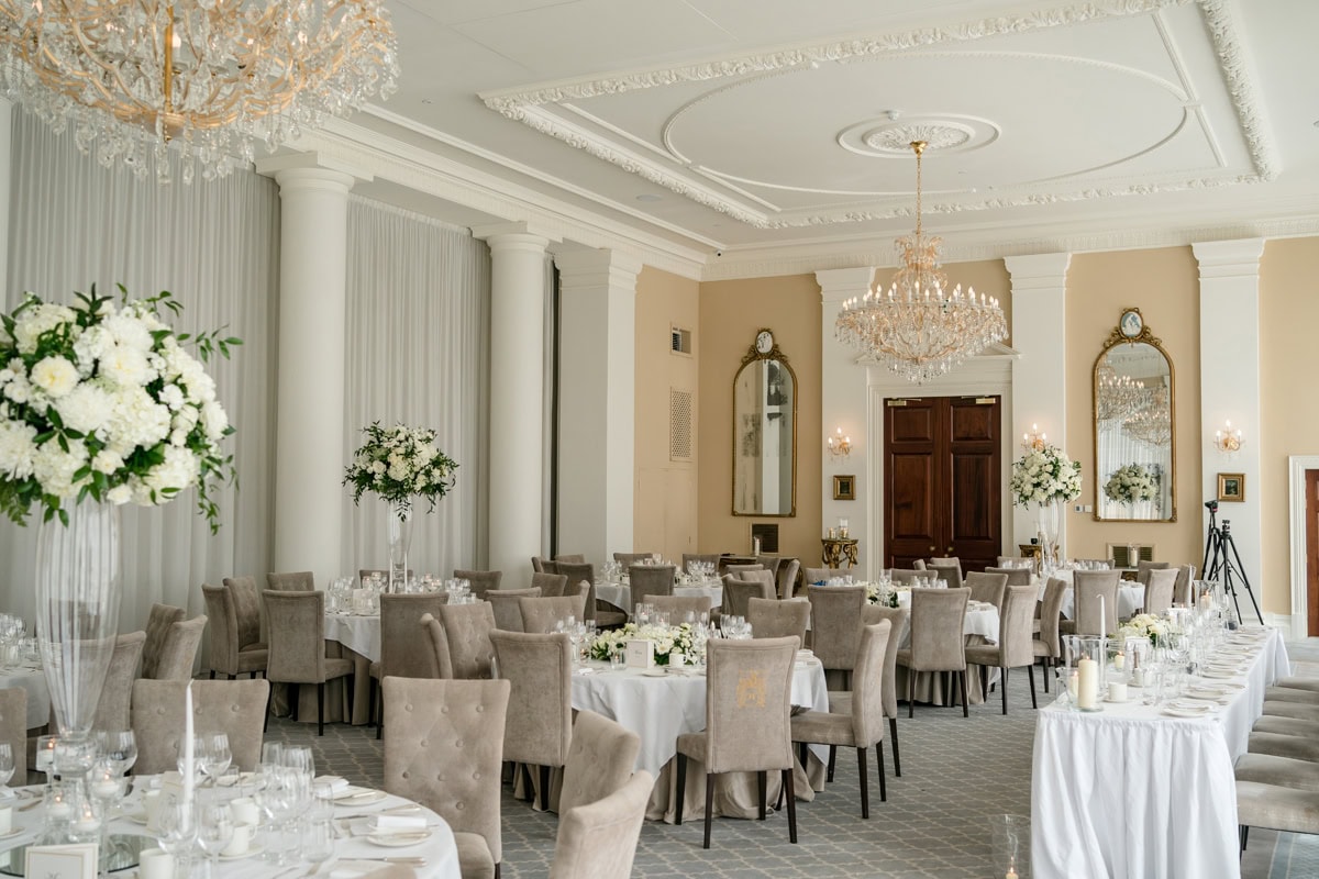 A grand room with large chandeliers set for a wedding breakfast
