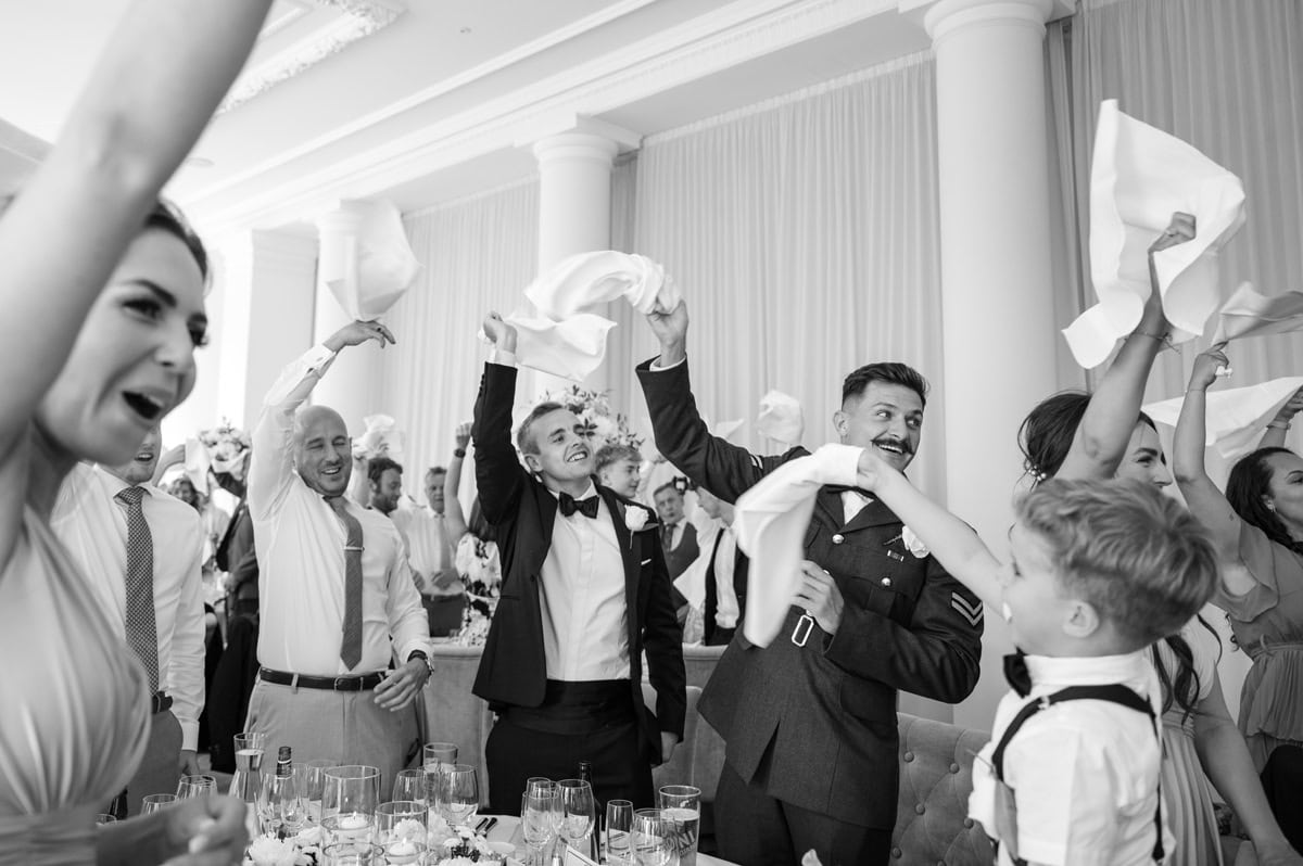 Guests enthusiastically waving napkins to welcome the bride and groom into the wedding breakfast