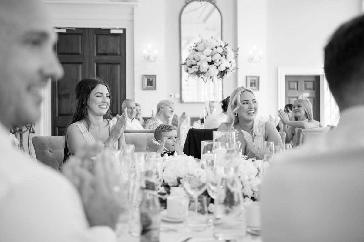 Wedding guests smiling and clapping during wedding speech