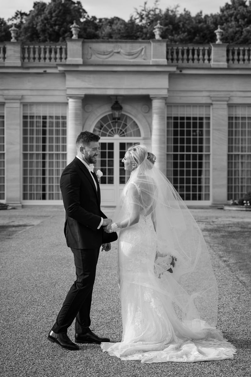 Romantic black and white photo of bride and groom in front of an orangery wedding venue